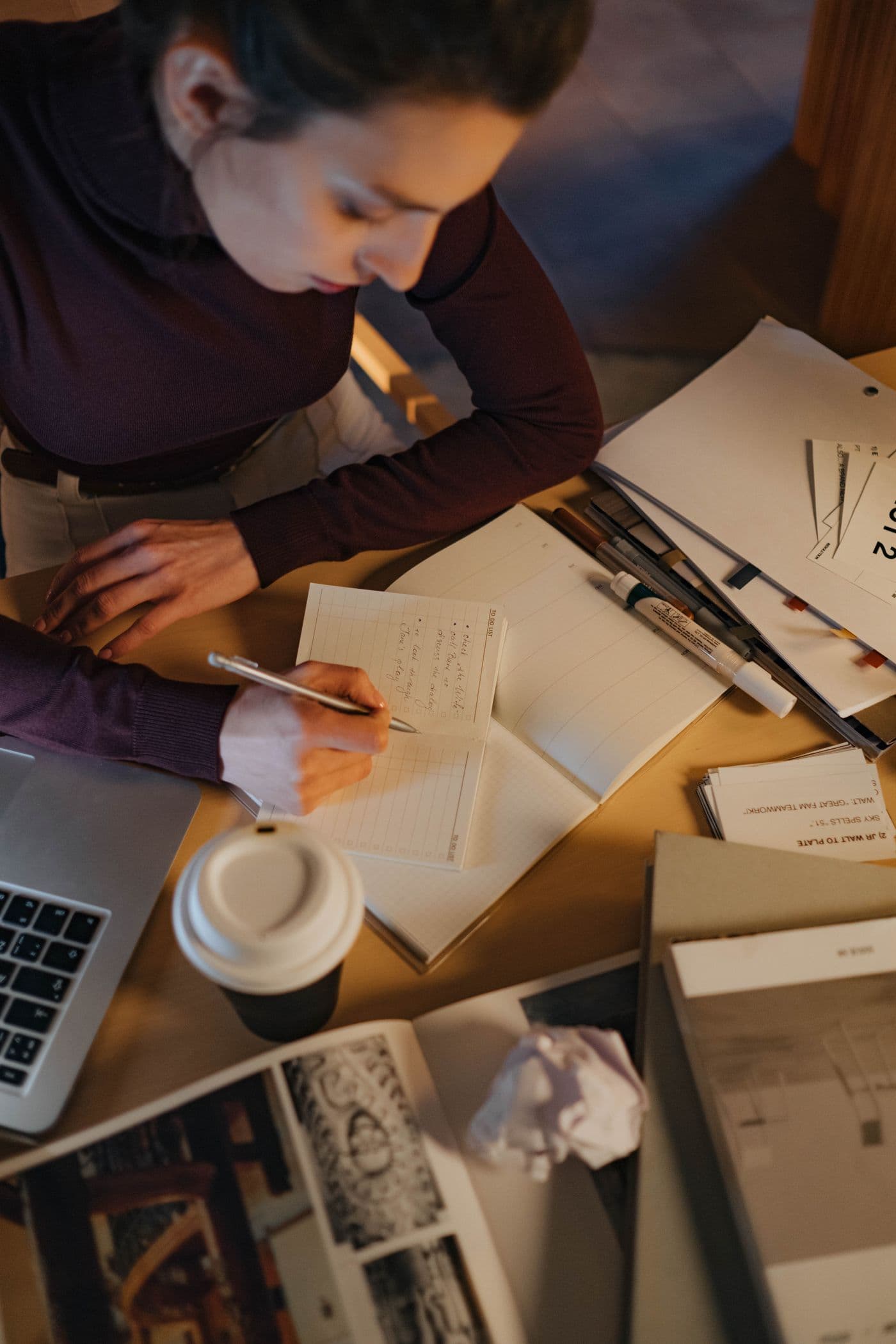 Overhead view of a writer drafting notes beside a laptop and coffee.